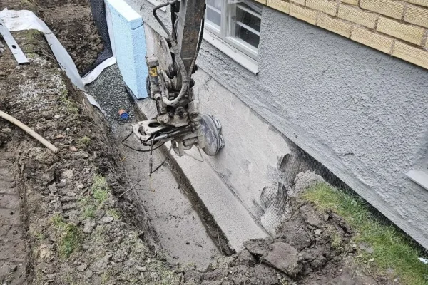 Fräser bort gammal asfalt beläggning på källarväggar.